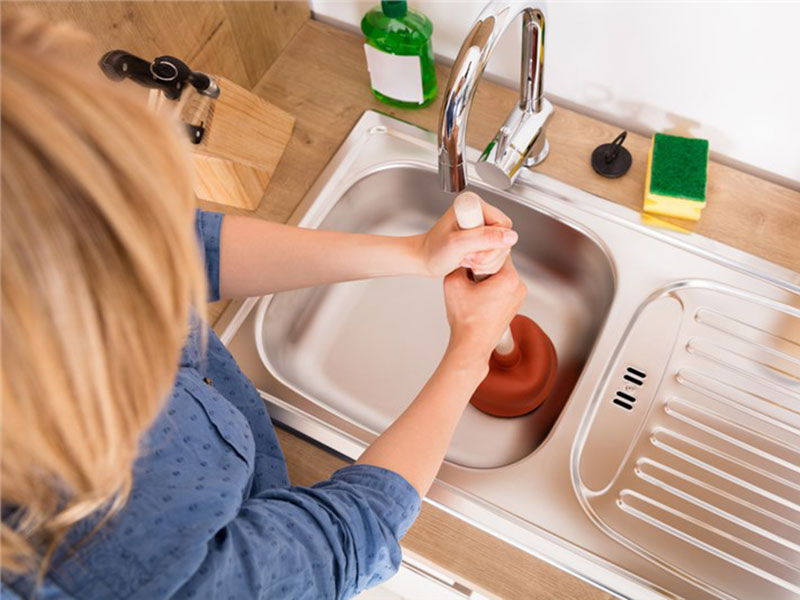 women trying to open clogged drain