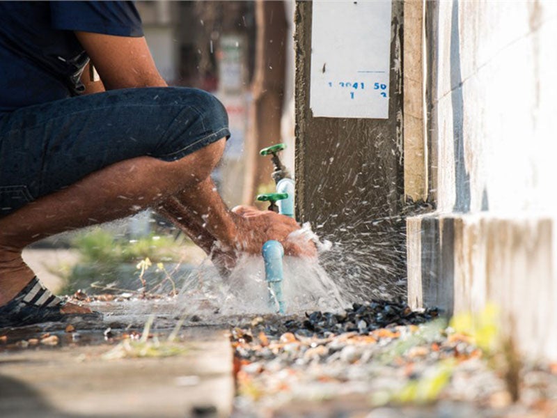 person repairing a broken water pipe