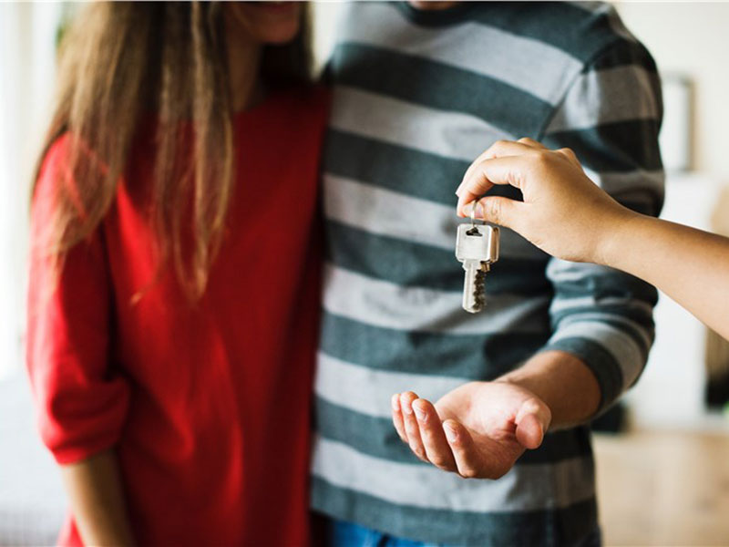 Person giving keys to a man and a woman
