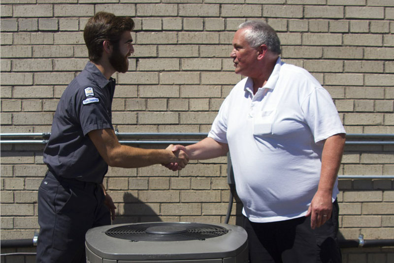 two men shaking hands over HVAC unit