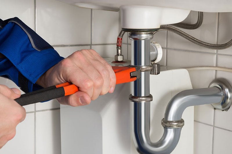 plumber repairing pipe under sink