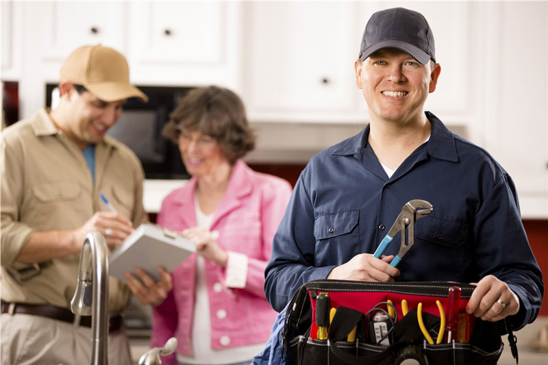 plumbers helping woman in kitchen