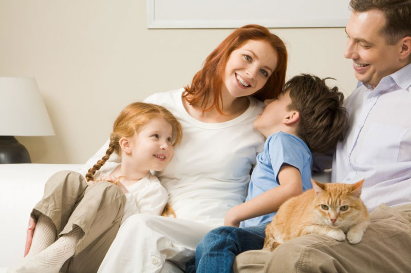 family smiling on couch inside home